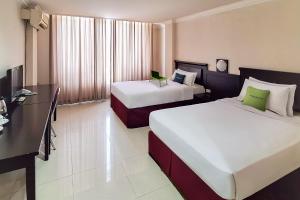 パランカラヤにあるUrbanview Hotel Surya Kahayan Palangkaraya by RedDoorzのベッド2台とデスクが備わるホテルルームです。