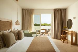 a bedroom with a large bed and a living room at Absolute Kiotari Resort in Asklipiḯon