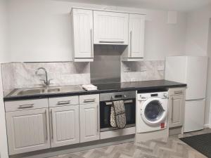 a kitchen with white cabinets and a washing machine at Local to Russells Hall Hospital in Brierley Hill