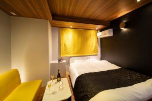 um quarto com duas camas e uma janela com uma cortina amarela em ホテル トランス 男塾ホテルグループ em Kobe