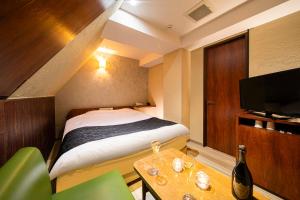 Schlafzimmer mit einem Bett, einem Tisch und einem TV in der Unterkunft ホテル トランス 男塾ホテルグループ in Kōbe