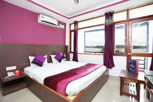 a bedroom with a large bed with purple walls and windows at JAZEERA RESORT in Port Blair