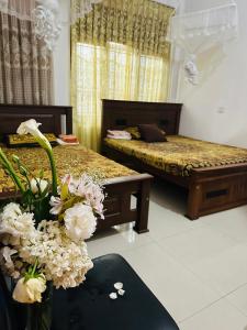 una camera con due letti e fiori sul pavimento di Golden Town Hostel a Tangalle
