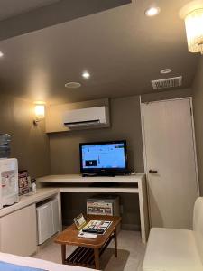 uma sala de estar com uma televisão e uma mesa de centro em ホテル トランス 男塾ホテルグループ em Kobe