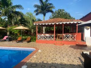 einen Pavillon mit einem Tisch und einem Pool in der Unterkunft Vila Marilyn in São Tomé