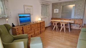 een woonkamer met een televisie en een tafel en stoelen bij Chesa Bellaval, Haus Leivra 2-Zimmerwohnung in Silvaplana