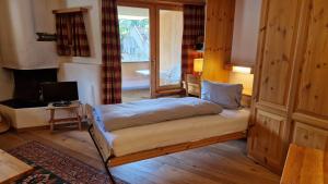 a bedroom with a bed and a desk and a television at Chesa Bellaval, Haus Rizza 1 1 2-Zimmerwohnung in Silvaplana