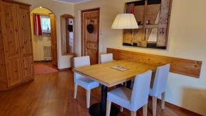 una sala da pranzo con tavolo in legno e sedie bianche di Chesa Bellaval, Haus Rizza 2 1 2-Zimmerwohnung a Silvaplana