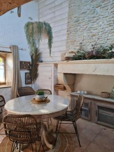 einen Tisch und Stühle in einer Küche mit einem Steinkamin in der Unterkunft Gîte L´aronde in Taillant