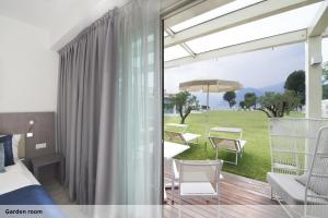 a bedroom with a balcony with a bed and chairs at Seven Park Hotel Lake Como - Adults Only in Colico