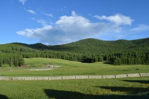 a fence in a field with mountains in the background at Wonder Mongolia Guesthouse and Tour Operator LLC in Ulaanbaatar