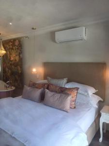 ein weißes Bett mit Kissen darauf im Schlafzimmer in der Unterkunft Thyme Wellness Spa and Guesthouse in Kapstadt