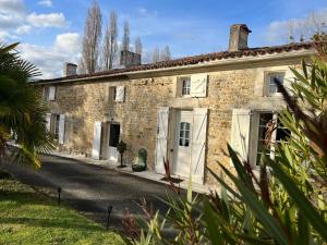 une vieille maison en pierre avec des portes blanches dans une rue dans l'établissement Gîte La Cassine, à Taillant