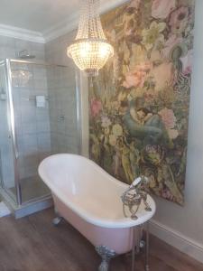 a bathroom with a chandelier and a bath tub at Thyme Wellness Spa and Guesthouse in Cape Town