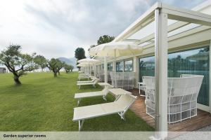 a row of white chairs and umbrellas on a deck at Seven Park Hotel Lake Como - Adults Only in Colico