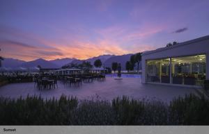 a sunset over a patio with tables and chairs at Seven Park Hotel Lake Como - Adults Only in Colico