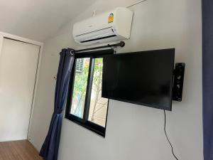 a flat screen tv on a wall next to a window at Namthip Homebeach in Baan Tai