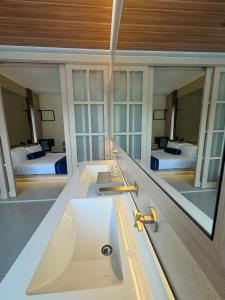 a bathroom with a sink and a mirror with two beds at Muzi Boutique Hotel in Ipoh