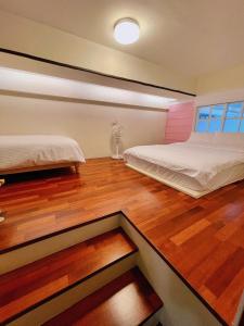 a bedroom with two beds and a wooden floor at 蹦噠噠包棟民宿 in Tainan