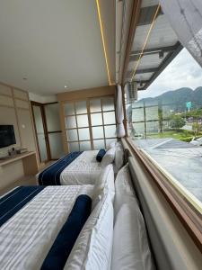 two beds in a room with a large window at Muzi Boutique Hotel in Ipoh