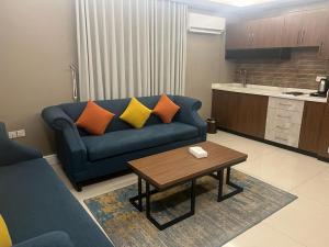 a living room with a blue couch and a table at Remaz Suites Hotel in Al Jubail