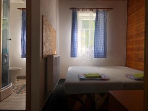 a bedroom with a bed and a window with blue curtains at Chalupa Anička in Pec pod Sněžkou