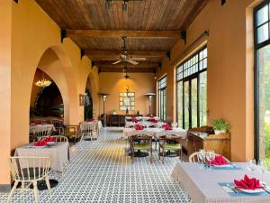 a restaurant with white tables and chairs and windows at Venus Hotel Tam Đảo in Tam Ðảo