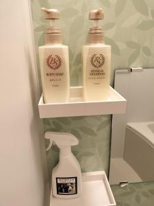 twee flessen wasmiddel op planken in de badkamer bij Hostel Belle Via Tokyo in Tokyo