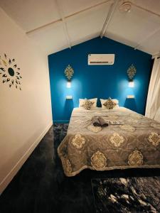 1 dormitorio con 1 cama grande y paredes azules en LAKSHDEEP COTTAGES en Canacona