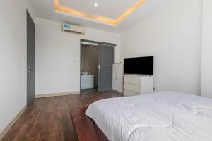 a white bedroom with a bed and a flat screen tv at Sunrise Villa Sanur in Sanur