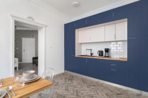 a kitchen with blue and white cabinets and a table at Cozy & Elegant Studio with Netflix Poznan Old Town by Renters in Poznań
