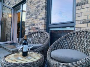 two wicker chairs with a bottle of wine and two glasses at Modern Home Near Edinburgh City in Bonnyrigg
