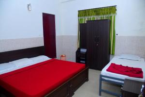 1 dormitorio con 2 camas con sábanas rojas y ventana en Muruz Stay Inn, en Gūdalūr