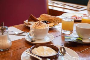 una mesa de madera con una taza de café y tostadas en Hôtel Le Bois Joli en Cauterets