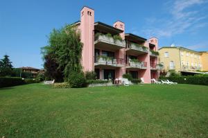 ein rosafarbenes Gebäude mit einem großen Hof davor in der Unterkunft Residence Virgilio in Sirmione