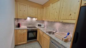 eine Küche mit Holzschränken und einem Waschbecken in der Unterkunft Chesa Bellaval, Haus Leivra 2 1 2-Zimmerwohnung in Silvaplana