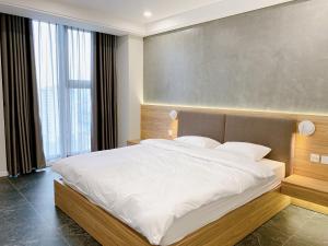 a bedroom with a large bed with white sheets at TSQ STAY Hotel Apartment in Hanoi