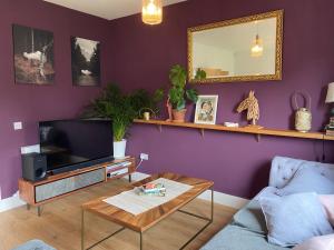 uma sala de estar com paredes roxas e uma televisão e uma mesa em Modern Home Near Edinburgh City em Bonnyrigg