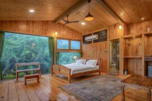 um quarto com uma cama e uma grande janela em The Arboreal Resort em Āmbavna