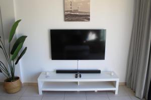 um centro de entretenimento branco com uma televisão numa parede branca em Pachi Beach Atlantic Garden Corralejo em Corralejo