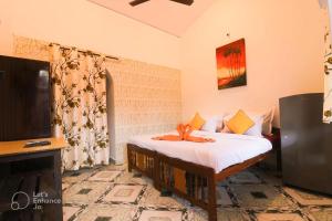 a room with a bed and a tv and a television at Ocean View Cottage in Calangute