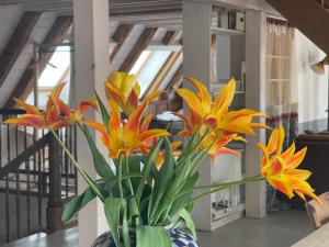 un vase rempli de fleurs jaune et orange sur une table dans l'établissement Boutique-Hotel Guesthouse Le Locle, au Locle