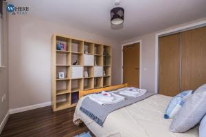 Stylish 3 Bed Apartment Aberdeen في أبردين: غرفة نوم مع سرير ورف كتاب