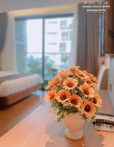 a vase filled with orange flowers sitting on a table at APEC MANDALA CONDOTEL PHÚ YÊn in Tuy Hoa