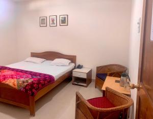 a bedroom with a bed and a chair in it at Hotel Devika in Dibrugarh