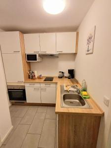 a small kitchen with a sink and white cabinets at Apartment/Wohnung direkt in Aschaffenburg in Aschaffenburg