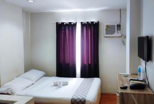 a bedroom with a bed and a window with avertisement at RedDoorz at Goldentown Hotel Davao City in Davao City