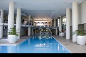 SS Luxury Apartments في كيب تاون: حمام سباحة كبير مع نباتات الفخار في مبنى
