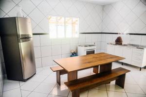 a kitchen with a wooden table and a refrigerator at Casa Flor da Serra in Nobres