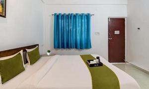 Cama grande en habitación con cortina azul en FabExpress Aqua Vista en Morjim